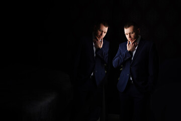 portrait of a man in a jacket in a dark room and reflection in the mirror..