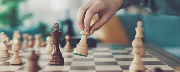 Boy playing chess and moving a piece