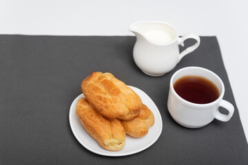 Homemade delicate profiteroles on table, cup of coffee. Traditional French eclairs. Top view