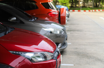 Closeup of front side of red  car with  other cars parking in outdoor parking area.