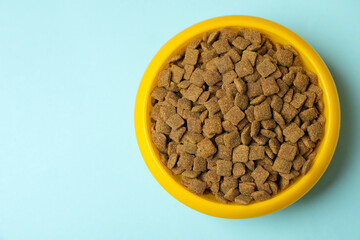 Pet bowl with feed on blue background