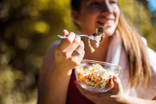 Woman Eating Salad After Exercise In The Park.