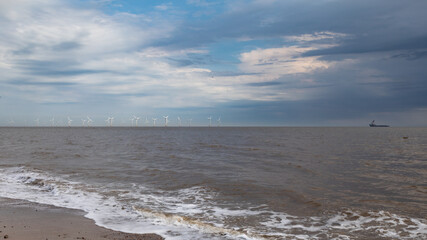 Fototapeta na wymiar Turbines on the horizon with a shipping vessel
