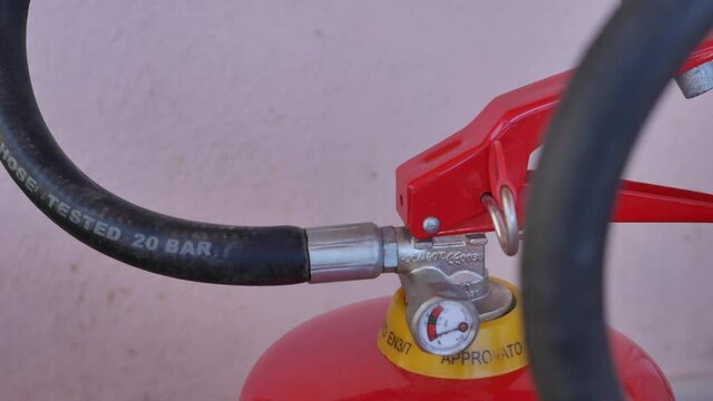 sliding close-up of two fire extinguishers with valves and pressure gauge in evidence of which one fire extinguisher is empty