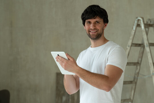 Man stand in new apartment, using tablet, choosing new design of house. Home repair