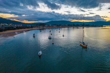 Fototapeta premium Aerial sunrise waterscape with boats and cloud cover