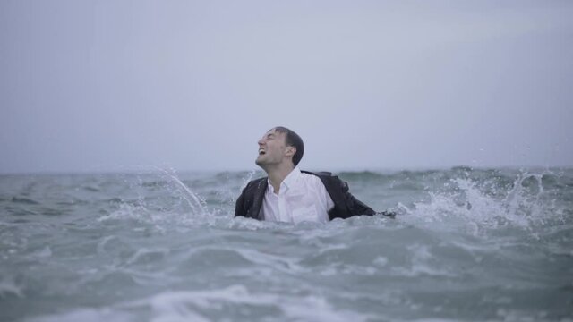Grown man reliving childhood playing in a ocean madly Barcelona