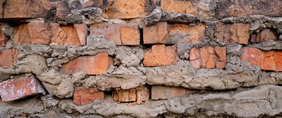 Demolished stone wall with exposed bricks, red, cracked and damaged brick wall