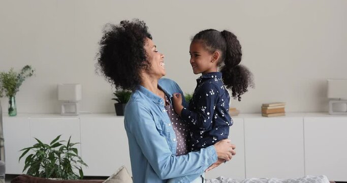 Loving African mom spend time with little 4s daughter, holding preschool adorable kid girl enjoy connection and communication feels love expressing care and protection. Mother Day celebration concept