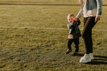 Fototapeta premium Mother and son play and run in the park, Mom holds her baby's hand