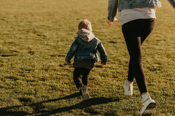 Fototapeta premium happy family having fun and jogging outdoors, mom and baby jogging in the park