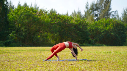asian chinese female lady yogi practise yoga stretches poses in the park in beautiful weather