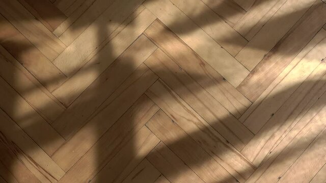Wooden floor with shadows from the window background. Wooden parquet floor in vintage retro room in morning sunlight. Empty vintage old interior with moving shadows of curtains