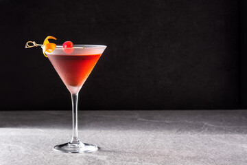 Traditional Manhattan cocktail with cherry on gray stone. Copy space