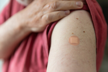 Caucasian man with a plaster on their arm after a vaccination injection