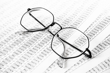 Worksheets or reports showing figures through eye glasses. closeup glasses on financial report. Accounting. financial data. Concept of Business and Finance research .