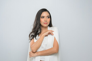 High fashion shot of young long black hair woman in white suit at studio shoot isolated on gray background.