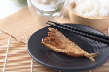 Fried dry fish on black plate eating with cooked rice, Asian cuisine