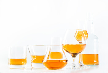 Hard strong alcoholic drinks, spirits and distillates in glasses in assortment: vodka, cognac, scotch, whiskey etc. White background, hard light