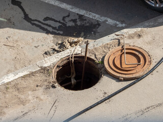 Open sewer hatch on a street. Repair of sewage, underground utilities, water supply system, water...
