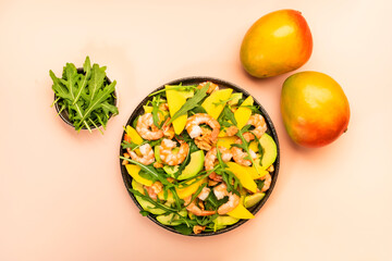 Seafood Salad with Mango, Shrimps and Avocado, Walnut, Spinach and Arugula. Top view, pink background