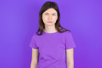 Fototapeta premium young beautiful Caucasian girl wearing purple T-shirt over purple background depressed and worry for distress, crying angry and afraid. Sad expression.