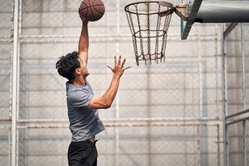 young asian basketball player attempting a dunk © imtmphoto