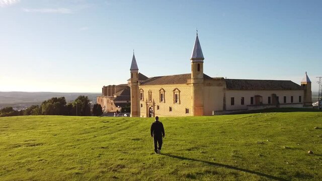 Person walking on a green meadow. In the background, an old building. The rest of the village can be seen in the background.