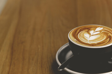 Nice cup of fresh brewed coffee with beautiful latte art on wooden table in cafe with copy space. Coffee break recreation relaxation