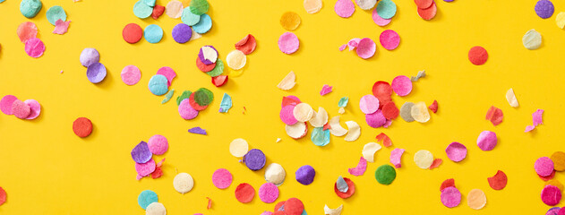 Colorful confetti on yellow background.Copy space