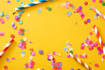Colorful confetti on yellow background.Copy space