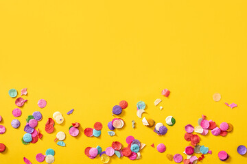 Colorful confetti on yellow background.Copy space