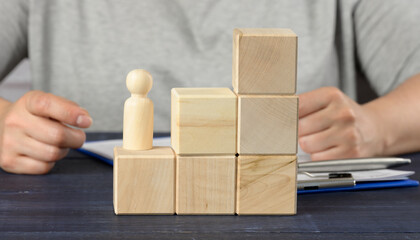 wooden cubes in the shape of a ladder and a figurine of a man. concept of career growth, goal...