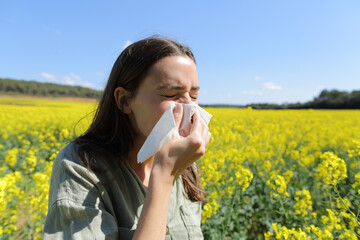 Allergic woman blowing nose in a field in spring