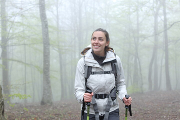 Happy trekker walking in a foggy forest