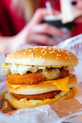 Close-up of a delicious fresh burger with cheese, onions in a fast food restaurant