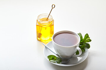 Black tea in white cup with mint leaves and honey. Calming and revitalizing tea, anti-stress and relaxation