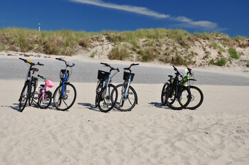 Der Weststrand Norderney mit geparkten Fahrräder: abgestellte Räder am Sandstrand, mit Dünen im Hintergrund.