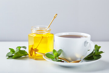 Black tea in white cup with mint leaves and honey. Calming and revitalizing tea, anti-stress and...