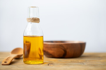 Olive oil in a bottle, a spoon, a plate on a wooden table on a white background. Copy space.