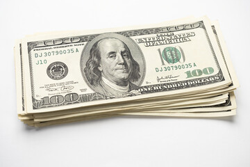 A money pile of stacked one hundred US banknotes with president Franklin portrait on white background. Cash of hundred dollar bills, paper money currency.