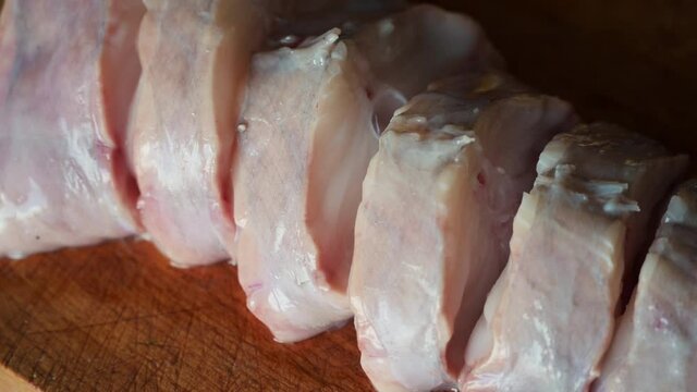 Close up shot of slices of monkfish arranged on a cutting board. Pan is panned along the cutting board. Mediterranean diet, food and health concept.