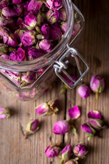 Dry pink roses, rose tea on a wooden background