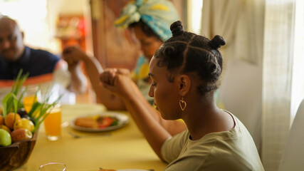Teen girl praying at breakfast table