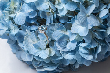 Fashion silver or white gold ring with a blue rectangular aquamarine stone. Elegant topaz ring for women. Jewelry ring with a precious stone. Blue flowers background.