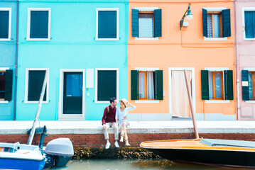 Young couple visiting on holiday Venice, Italy - Two tourists sitting on Venetian canal on summer...