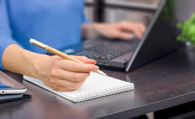 woman working on laptop and writes in notepad