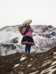 Indigenous local in traditional colourful andean clothes at Vinicunca Rainbow Mountain, Cuzco Peru Andes in snowy winter