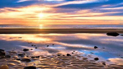 Sunrise over the North Sea and Brora beach in the Highlands with colourful reflections in the calm waters of a tidal pool