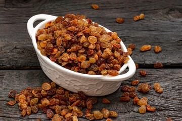 Raisins are beautifully dried highest grade in white bowl. Delicious background or wallpaper. Grape Raisins as an abstract background texture
